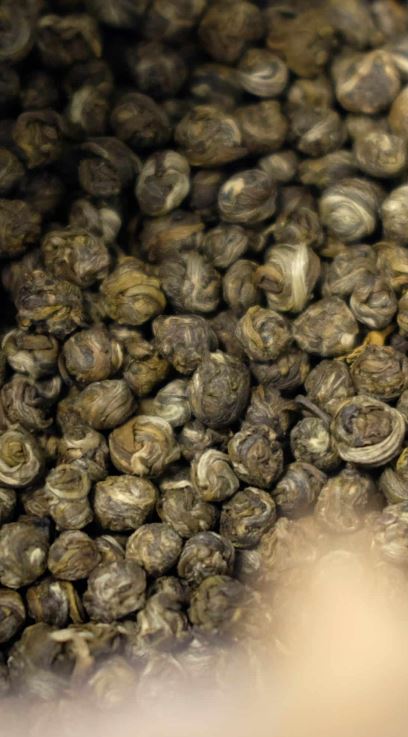 Handgerolde theeparels en verse witte jasmijnbloesem